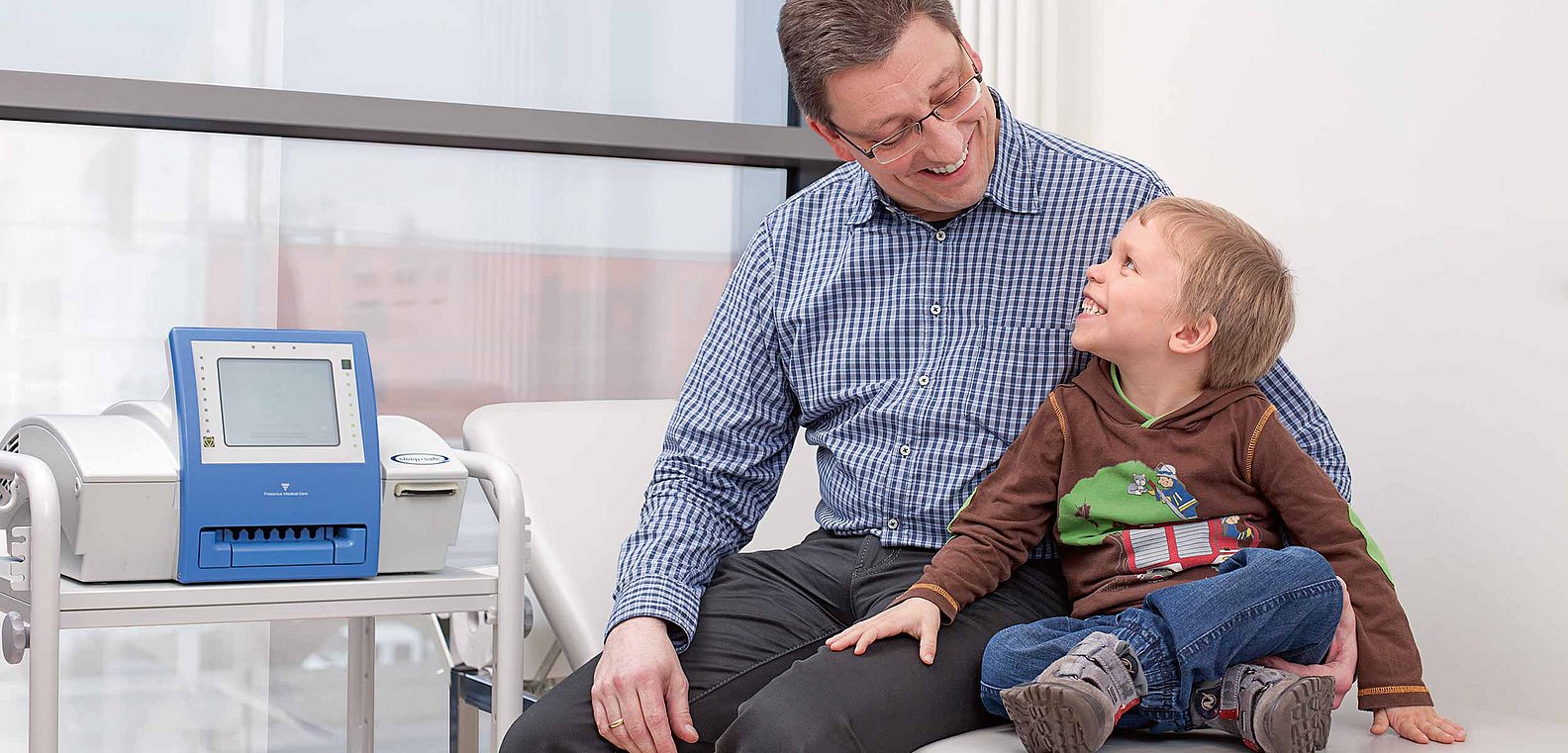 Father sitting with son on hospital bed